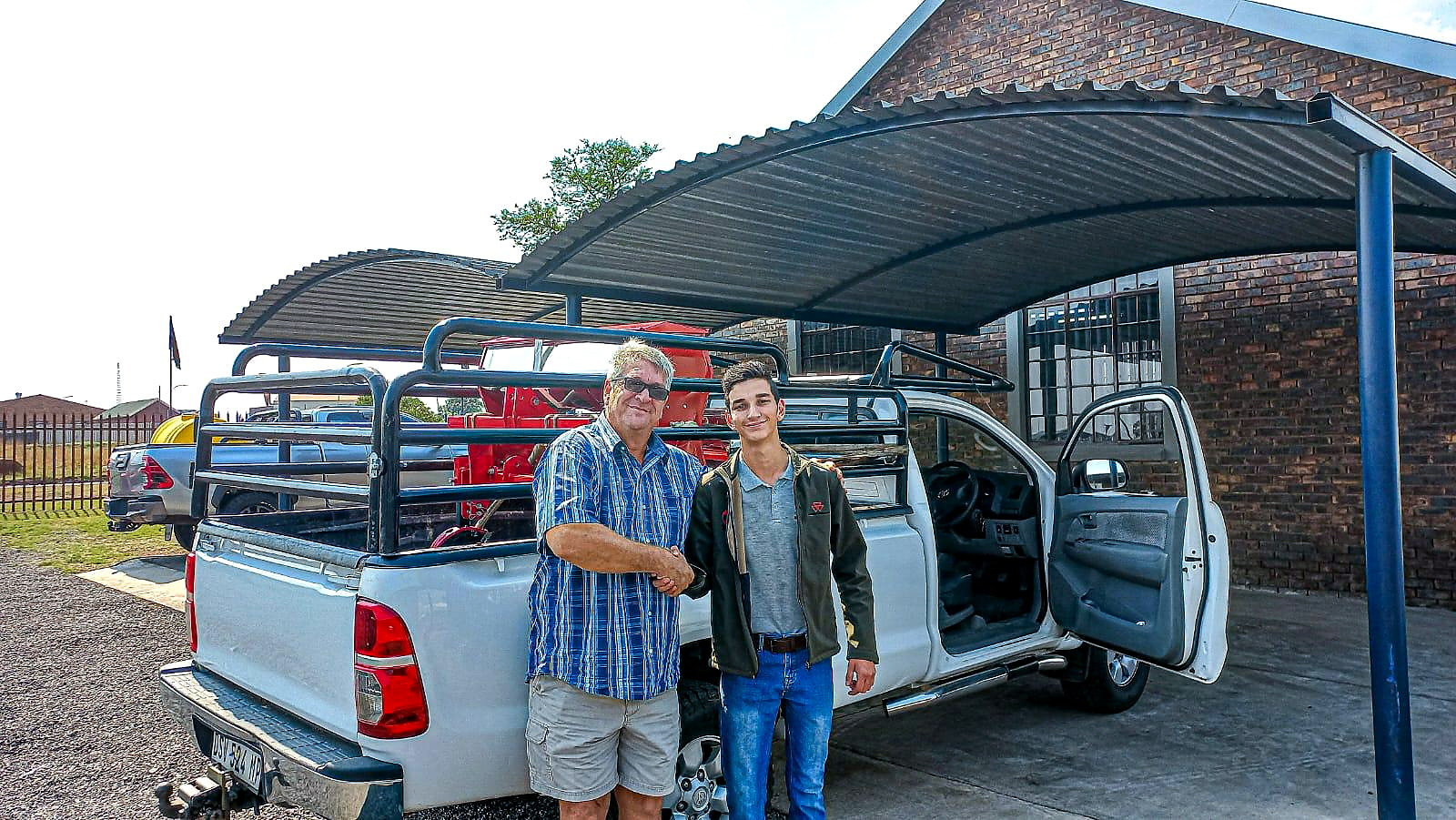 Morne shaking hands with a customer beside a white bakkie at a handover