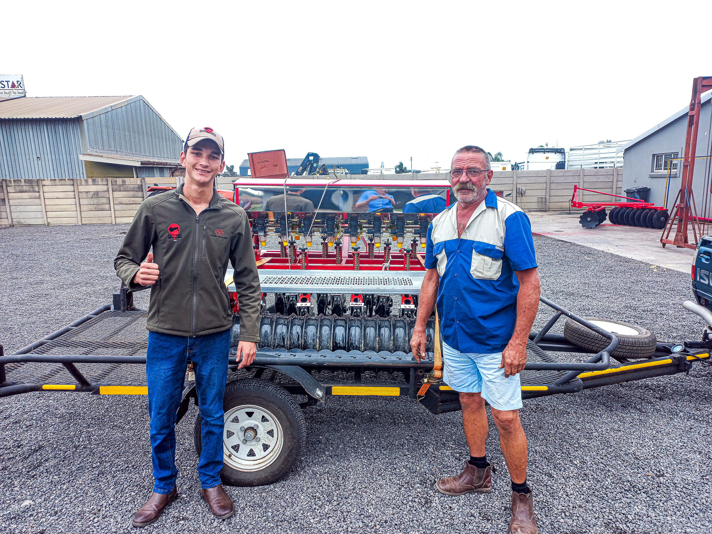 Morne and a customer standing beside an implement loaded on a trailer